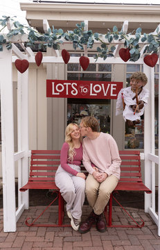 Couple & Cupid during February at Gardner Village - couple sitting on bench with cupid overhead 
