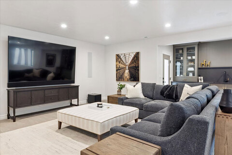 Down to Earth Projects<br>Symphony Homes Parade Ninth + North Design - basement family room with gray sofa and large tv 