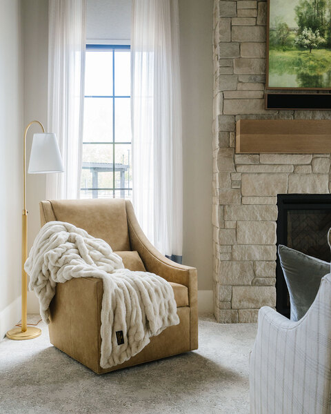 Down to Earth Projects | Utah Valley Parade at The Legacy at Meadow Ridge - Down to Earth Projects | Utah Valley Parade at The Legacy at Meadow Ridge - camel chair with light next to fireplace